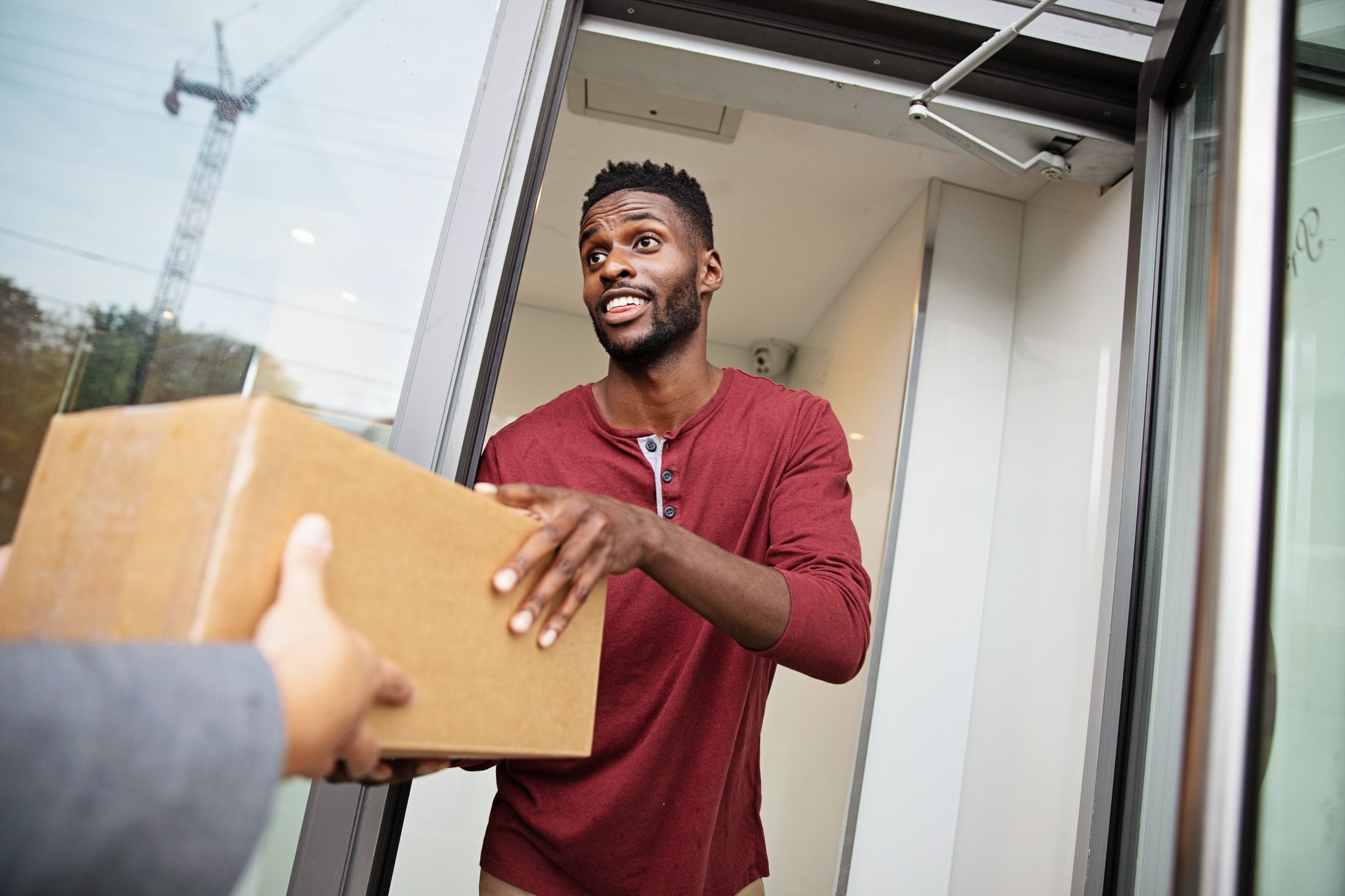 A man accepting a delivery box at his door.