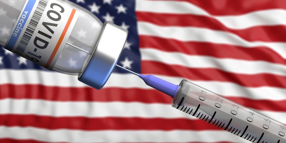 COVID-19 vaccine is drawn up in front of an American flag.