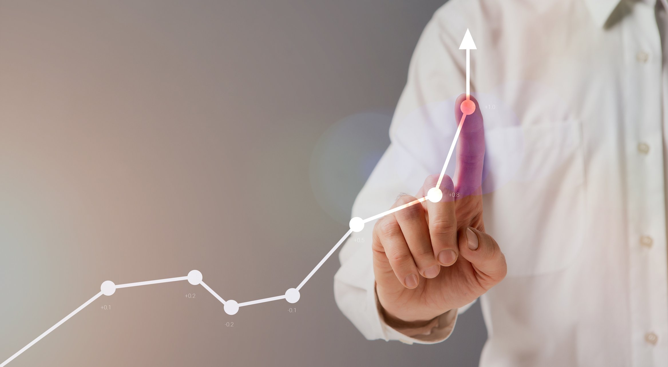 Man's finger pointing to a point on a line that's trending up