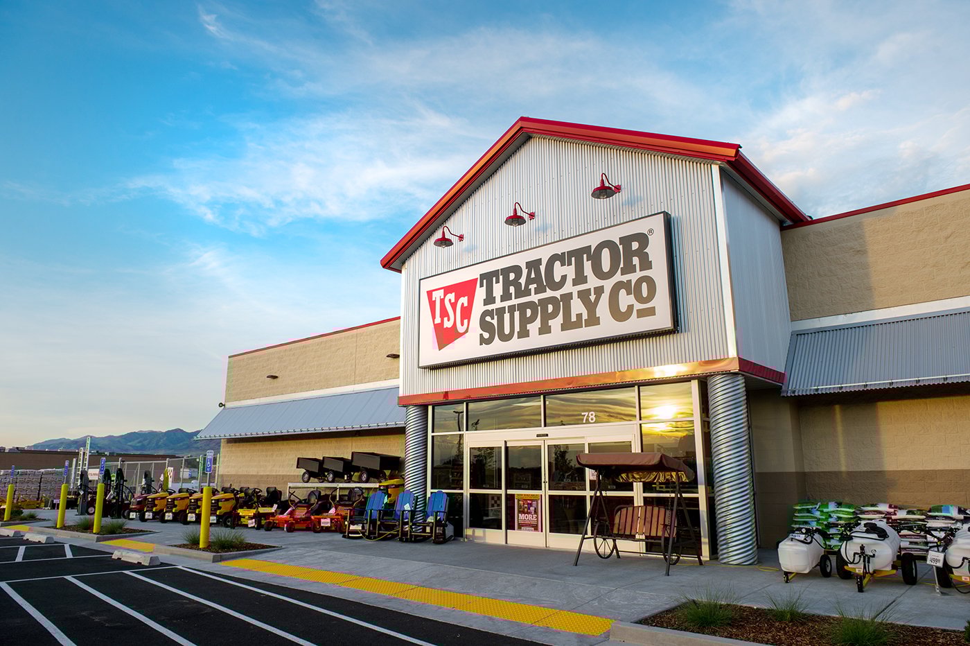 A Tractor Supply Company storefront, illuminated by morning light with a partly cloudy sky above.