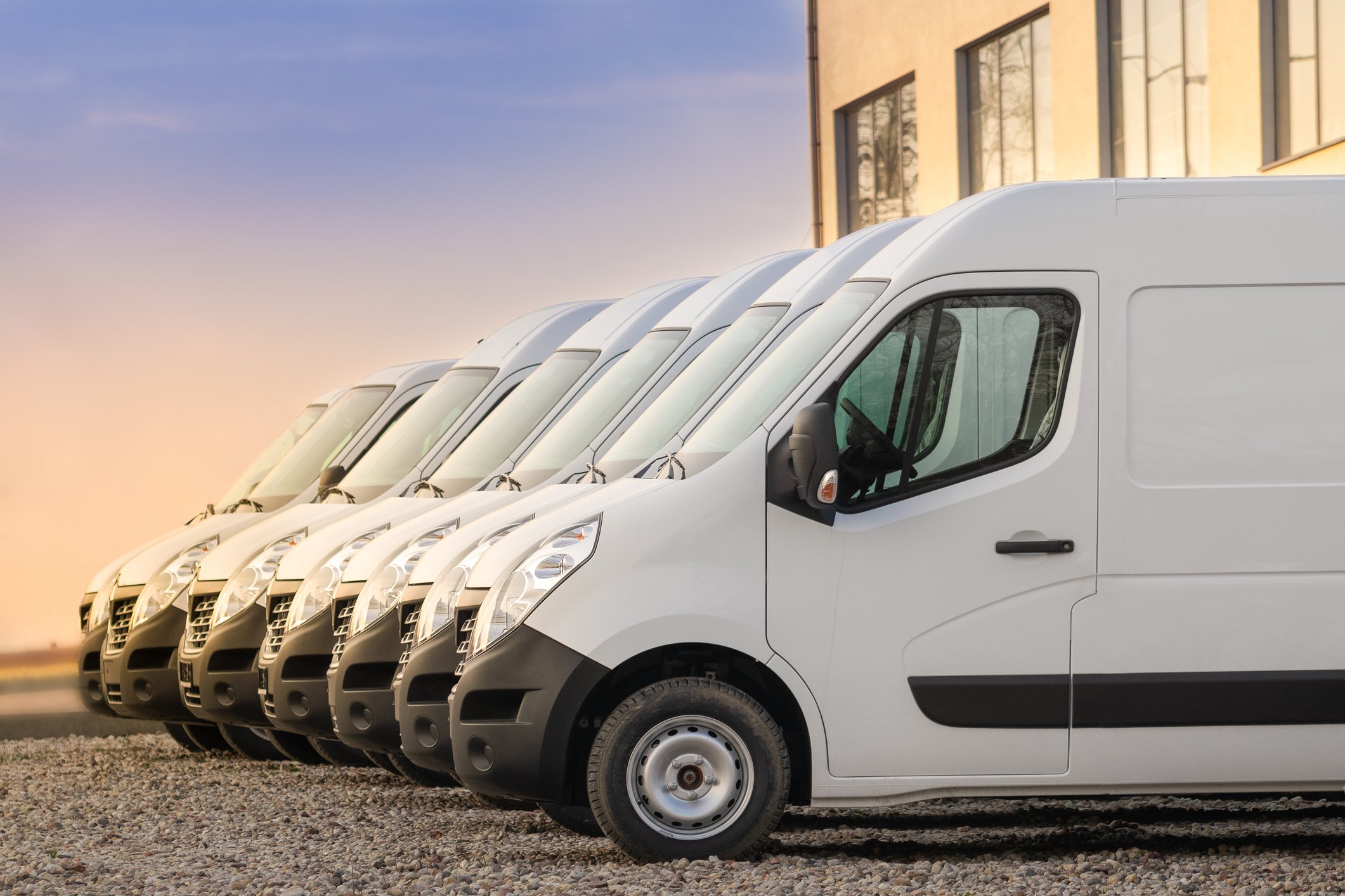 A side view of a fleet of white light commercial vans. 