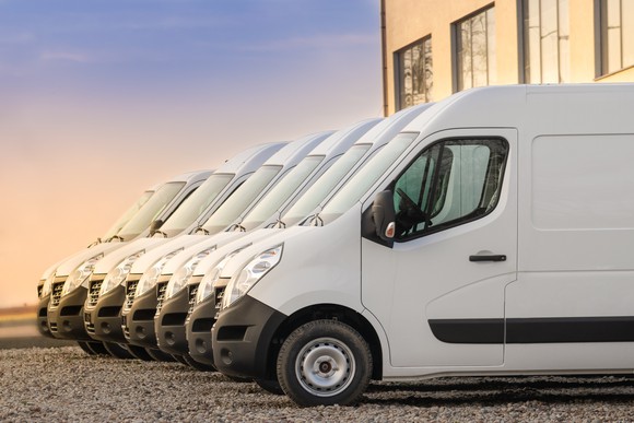 A side view of a fleet of white light commercial vans. 