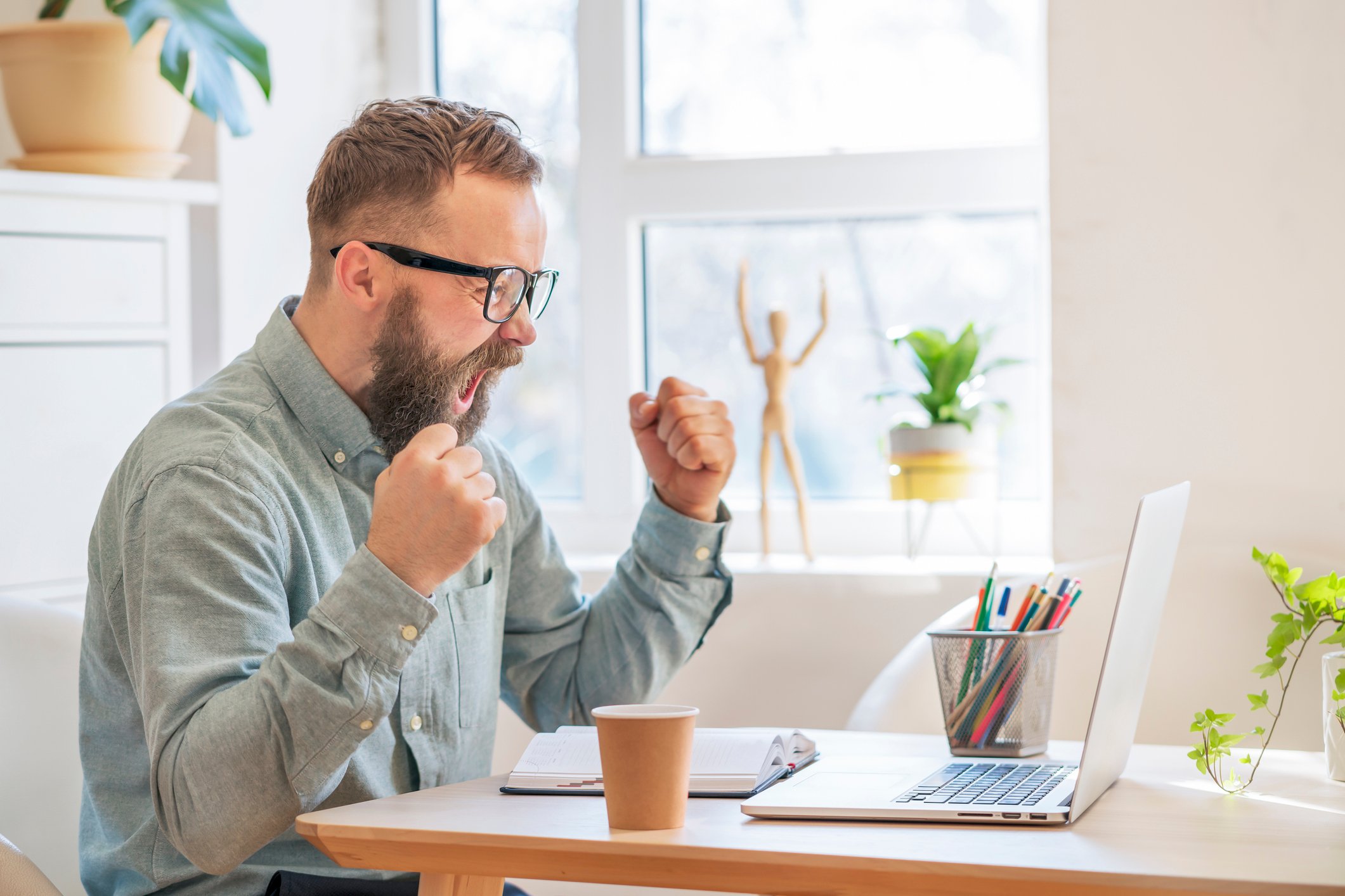 Man looking at computer and cheering with excitement