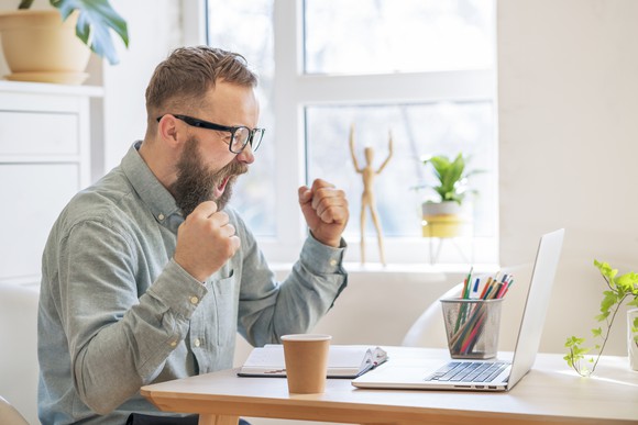 Man looking at computer and cheering with excitement