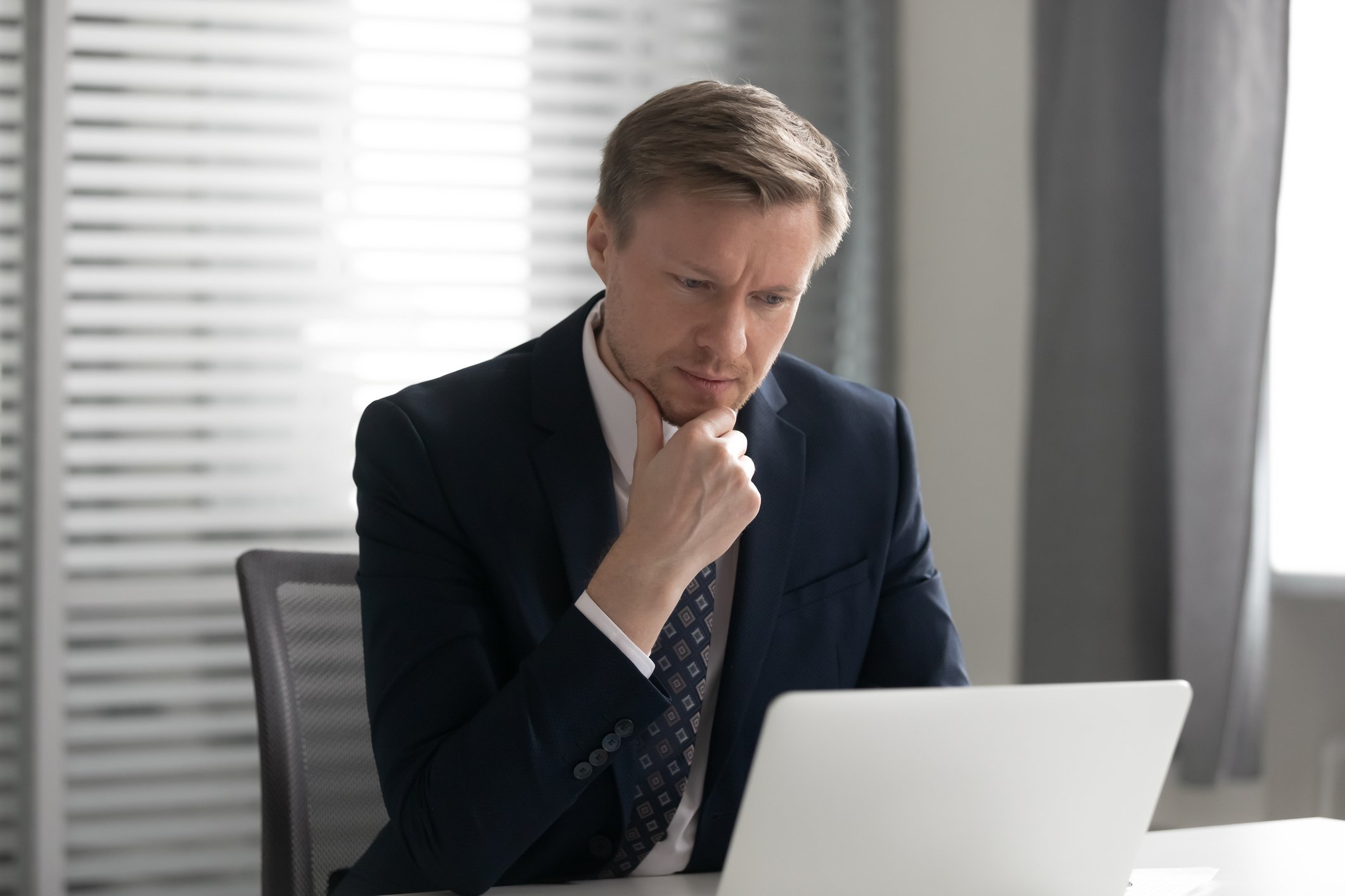 An investor considers information on a laptop.