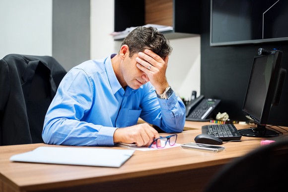 Man at desk holding his head