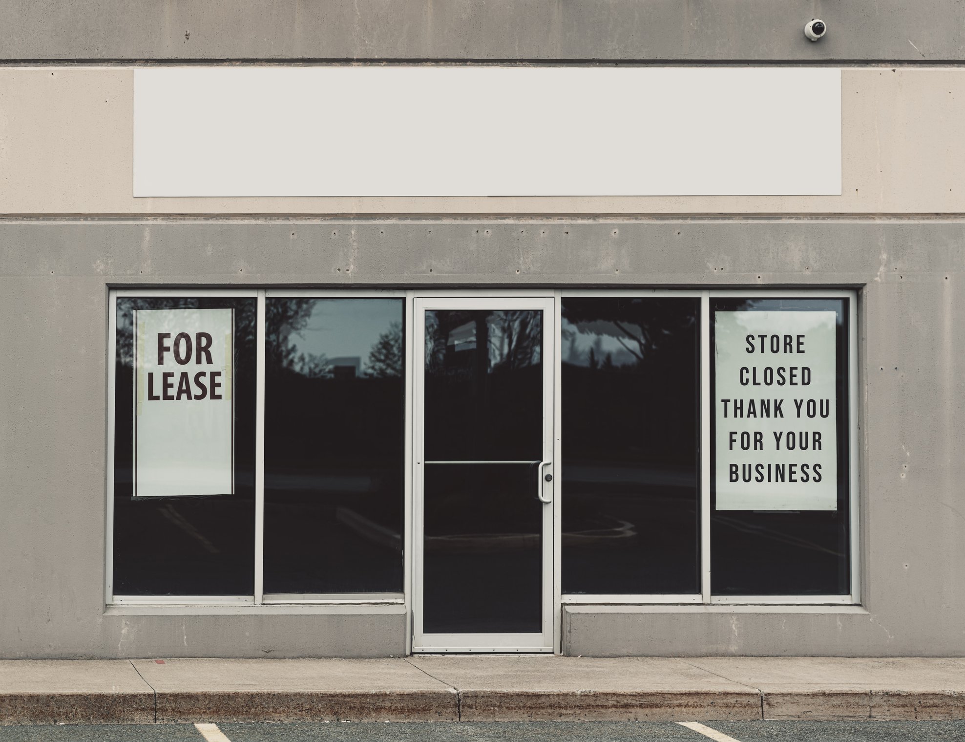 A storefront with a For Lease sign and a sign saying the store is closed.