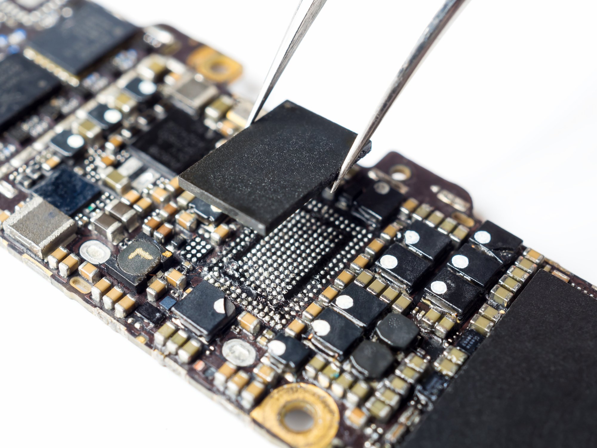 Tweezers lift a chip out of a smartphone circuit board.