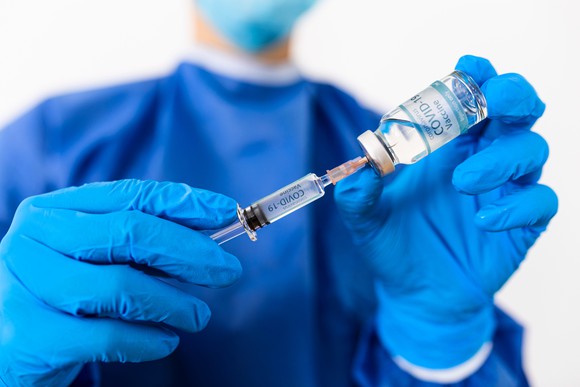 Physician holding vaccine vial and syringe
