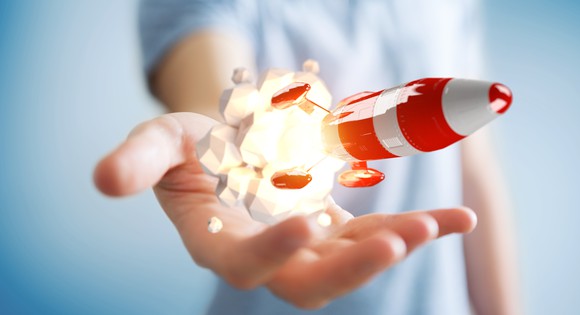 A miniature rocket launching from a person's hand.