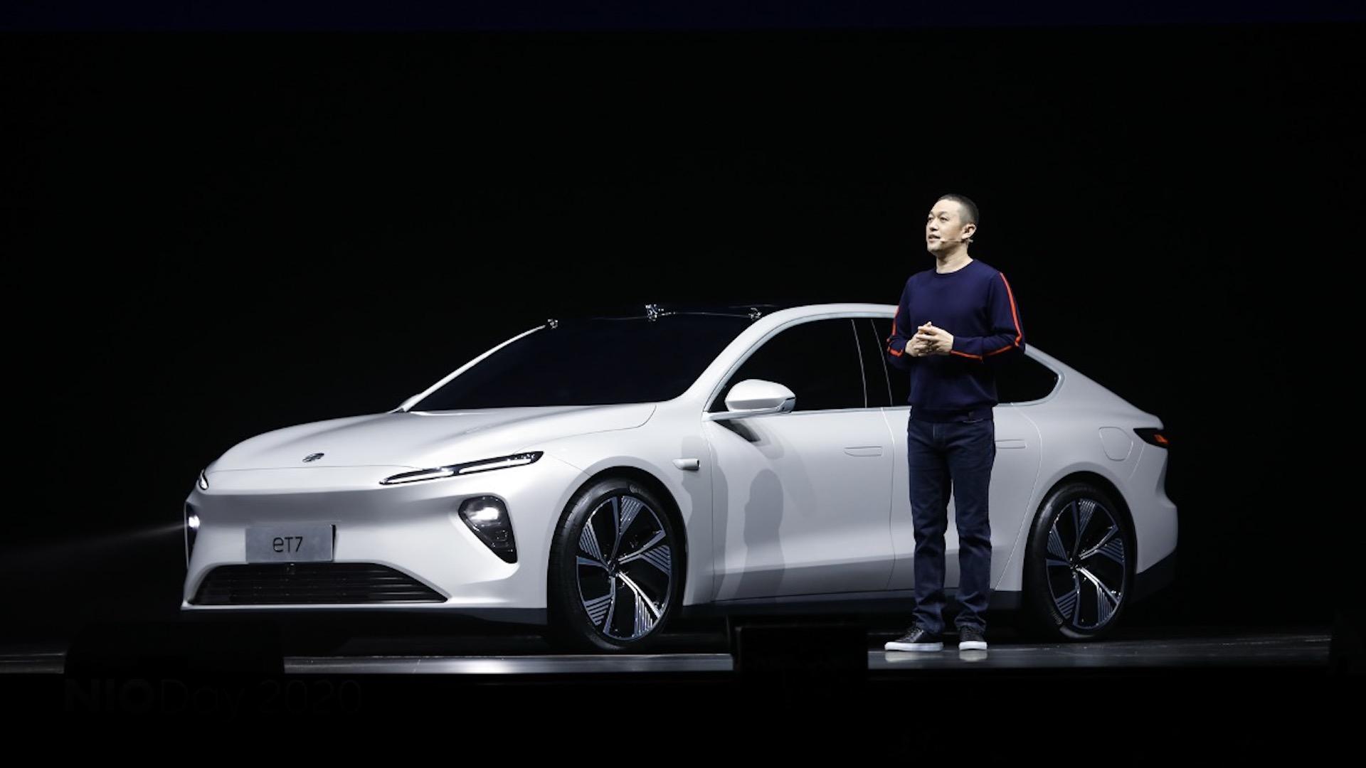 Li is shown on stage, standing next to a white electric luxury sedan. 