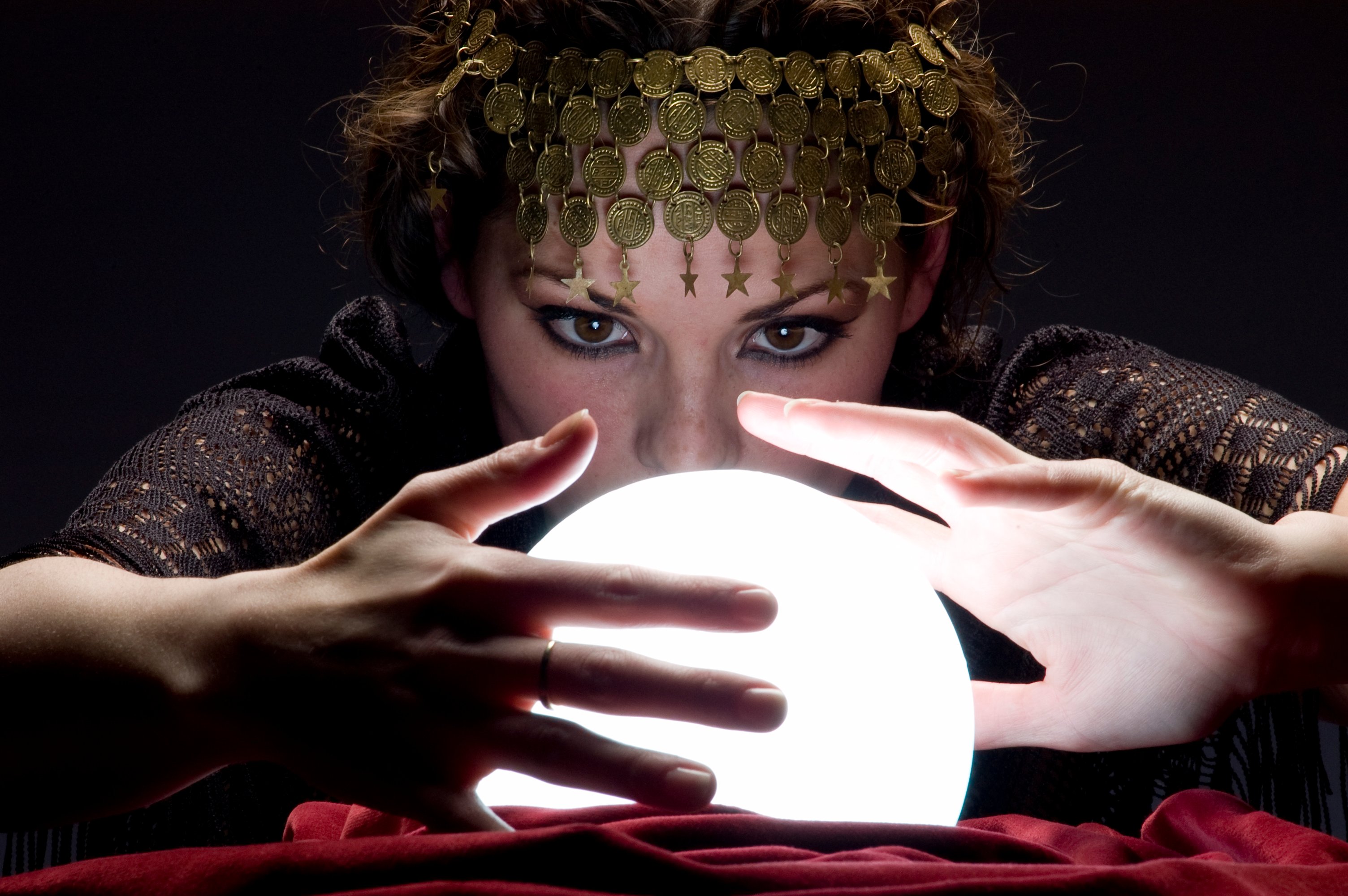 A fortune teller looking into a glowing crystal ball.