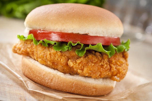 A fried chicken sandwich topped with lettuce and tomato, standard fast food fare.