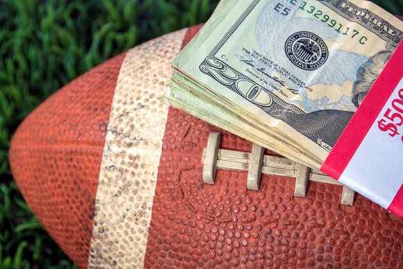 Stack of twenty-dollar bills on top of a football