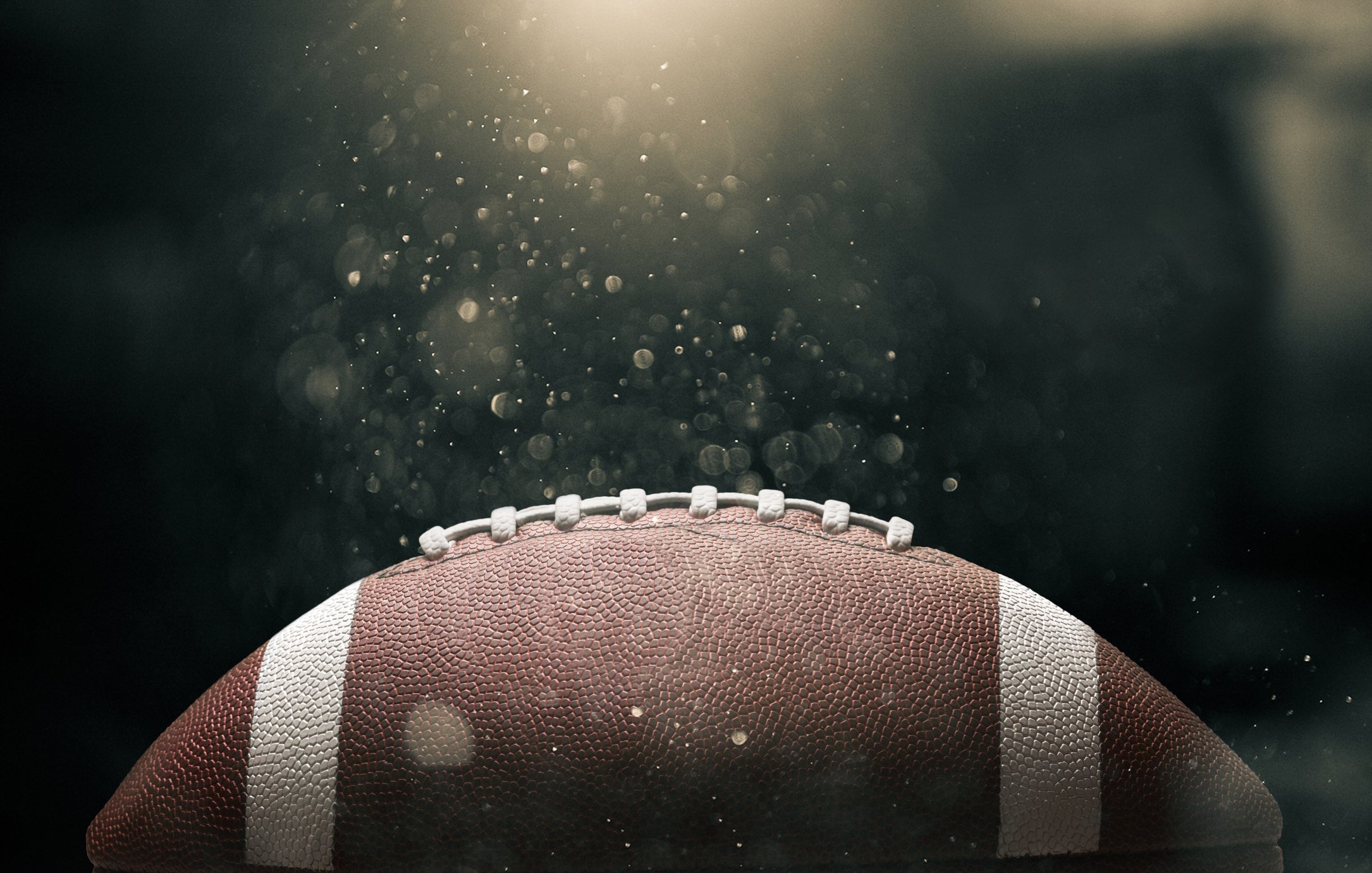 American football ball on black background illuminated. 