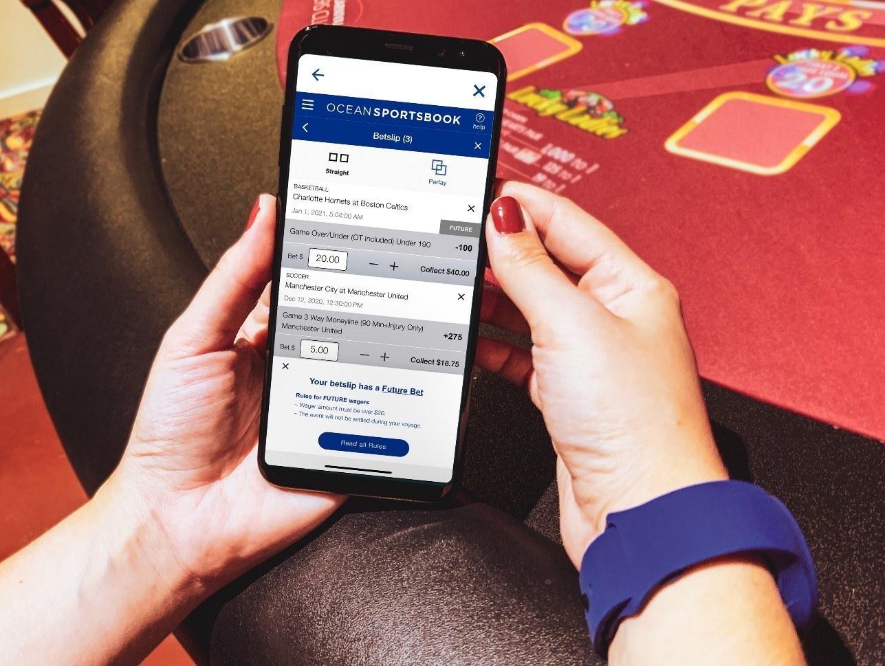 The hands of a woman using the Ocean Sportsbook app on her smartphone.