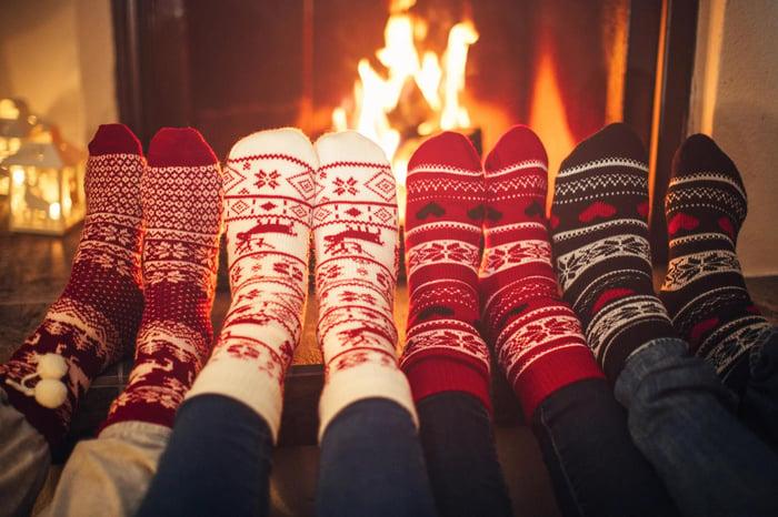 Four pairs of feet with socks in front of a fire.