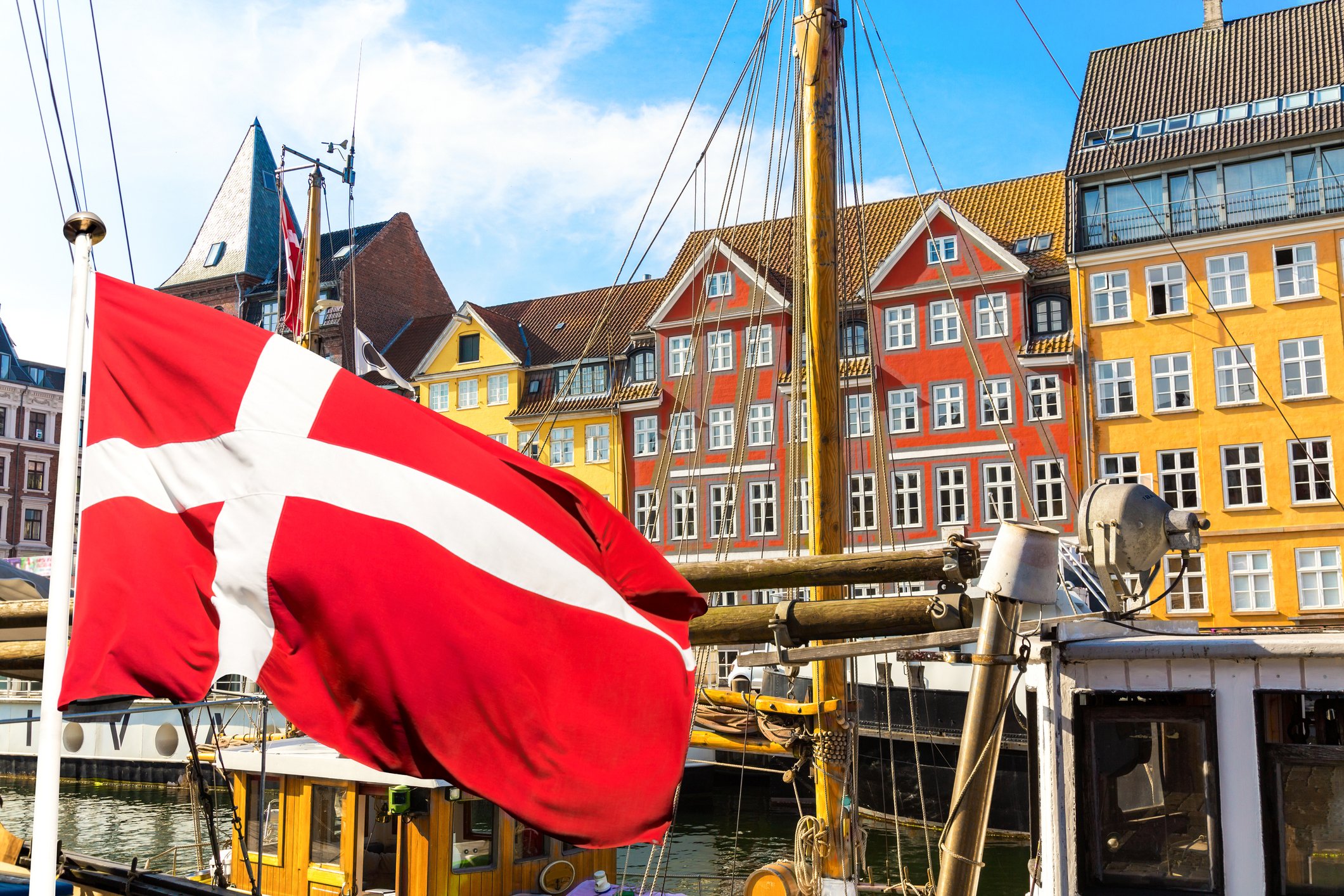 Colorful houses in Copenhagen, Denmark, with a Danish flag in the foreground.