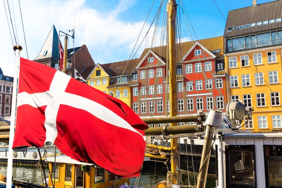 Colorful houses in Copenhagen, Denmark, with a Danish flag in the foreground.
