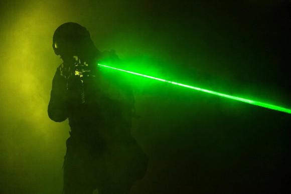 Person holding gun with green laser sight.