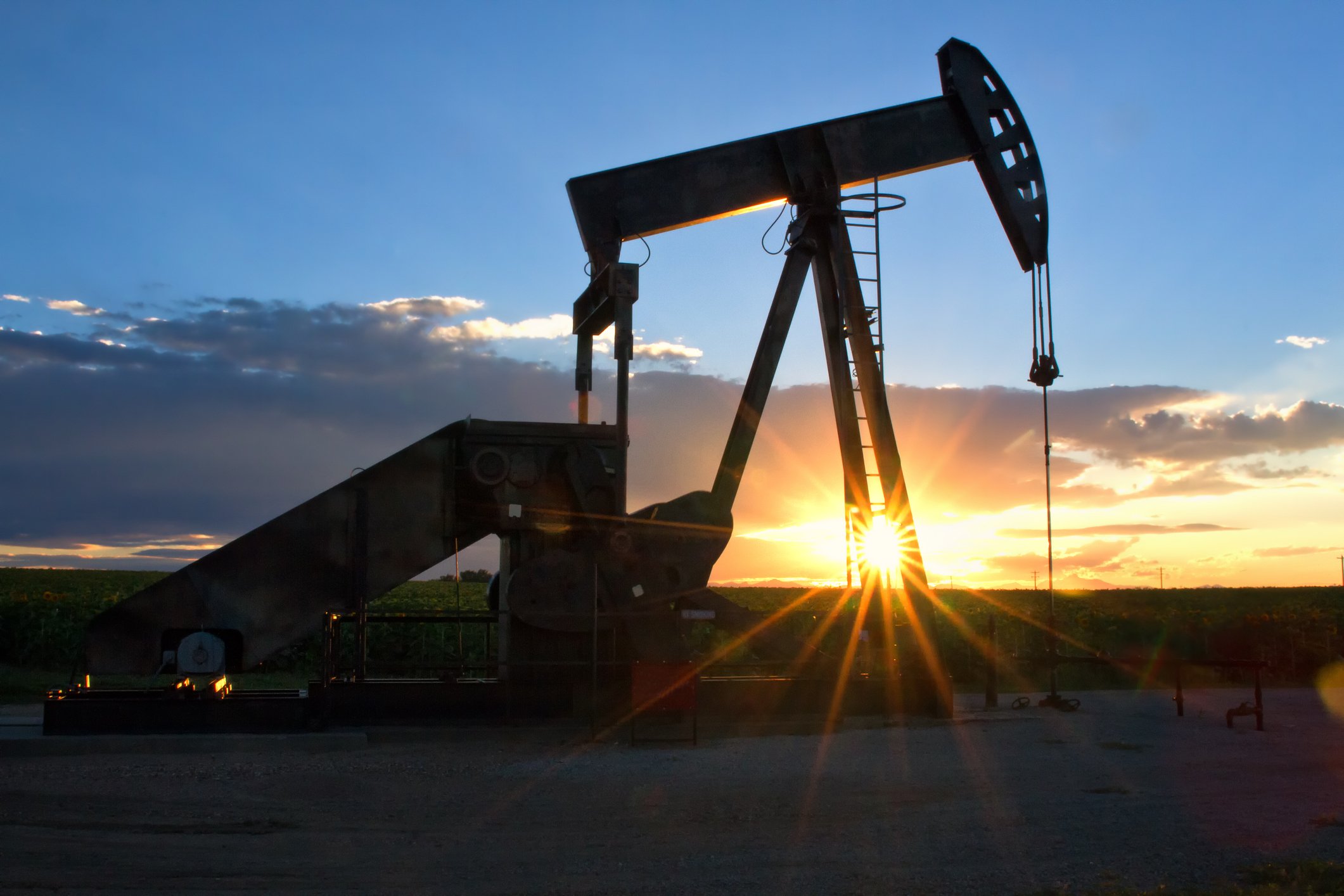 An oil pump jack with the sun setting in the background