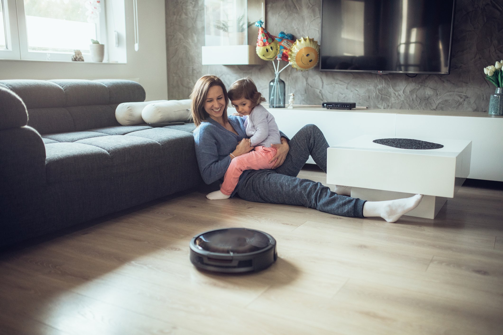 A mother and daughter looking at a robot vacuum cleaner.