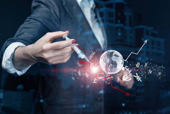 Person holding a syringe near a globe, with money symbols and stock arrows in space.