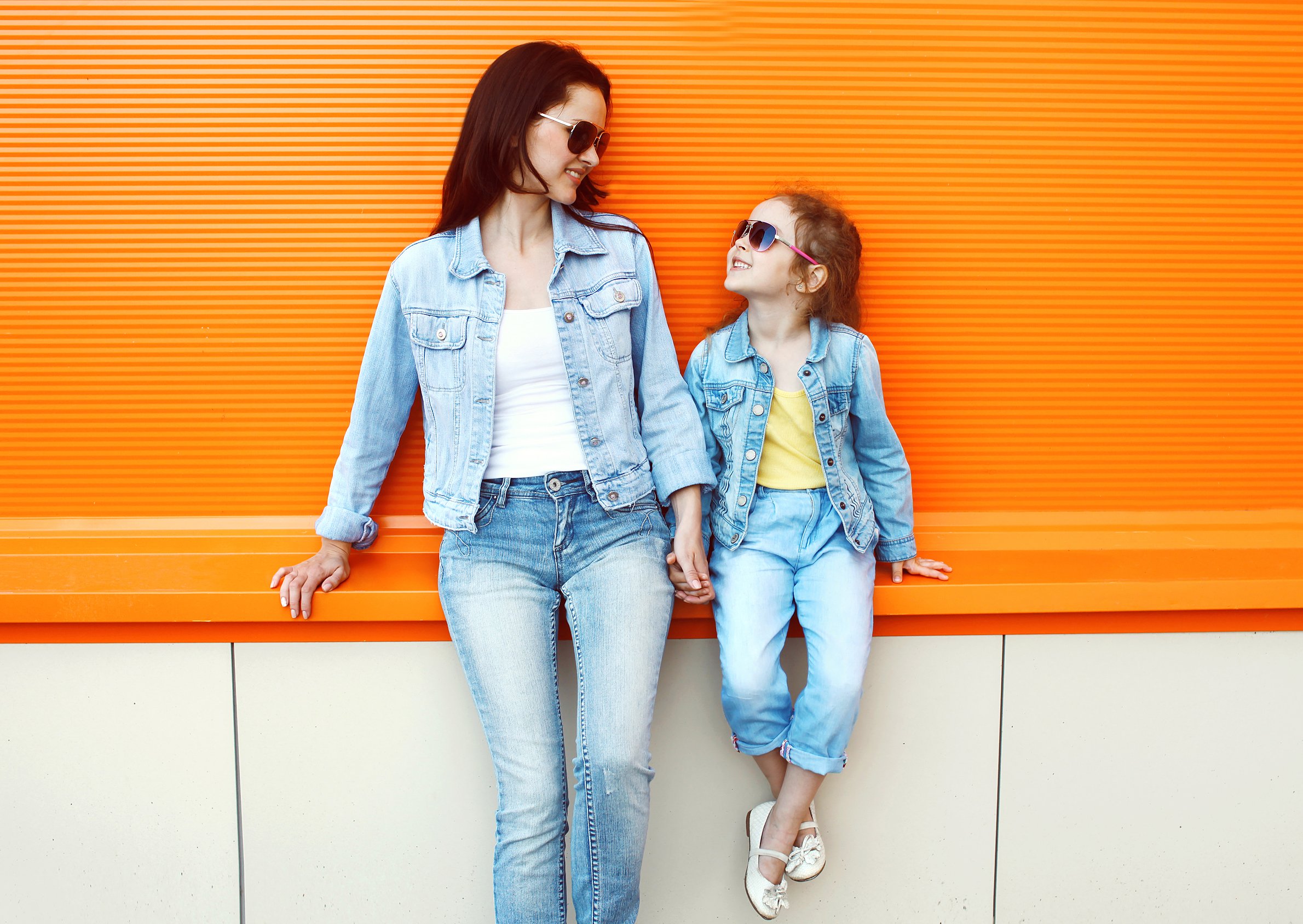 A mother and daughter wearing sunglasses and denim.