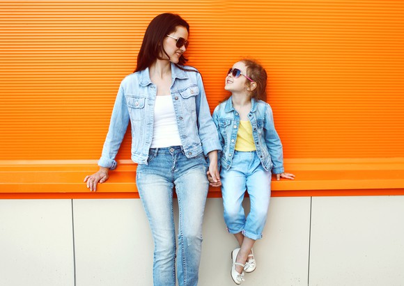 A mother and daughter wearing sunglasses and denim.