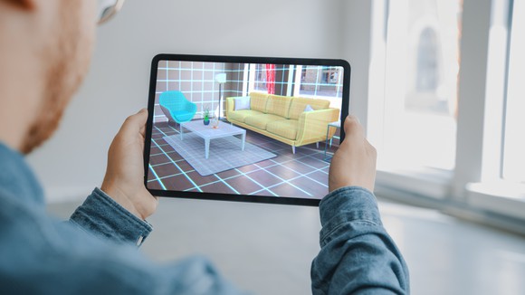 A person using a tablet and augmented reality to envision a living room layout.