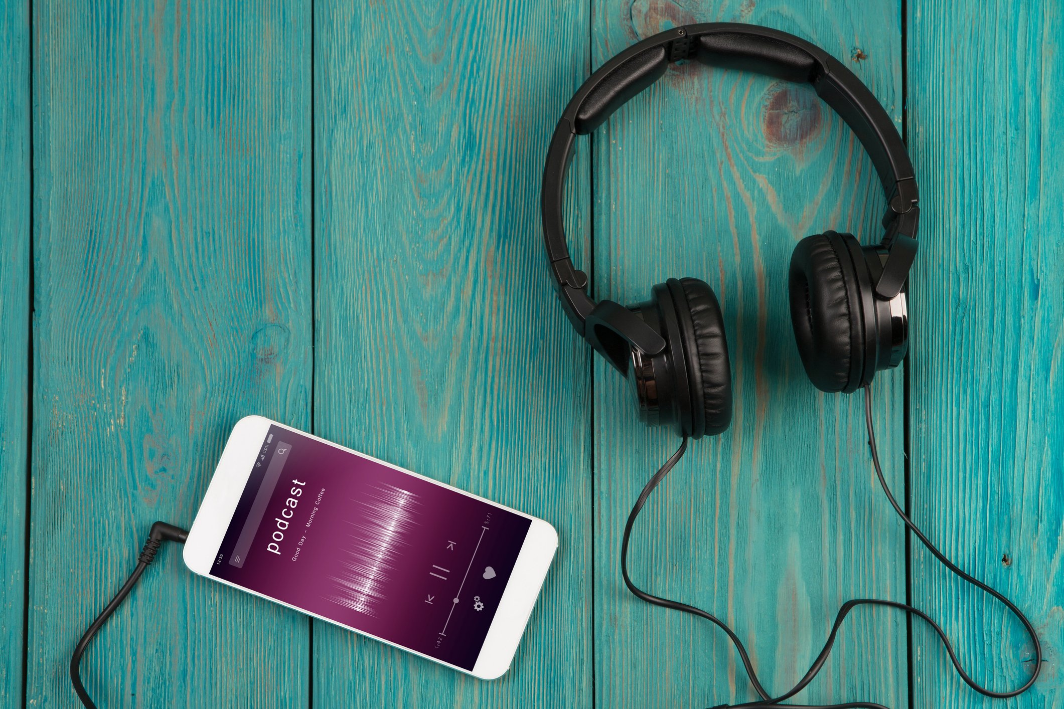 Smartphone and headphones on a wooden table. 