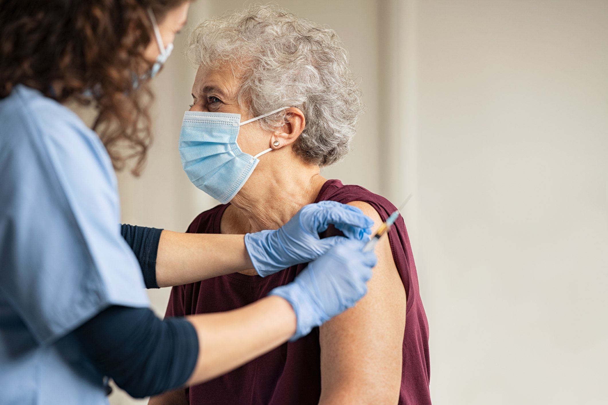 A health professional administers a COVID-19 vaccine to a lady. 
