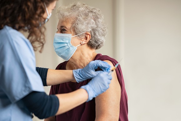A health professional administers a COVID-19 vaccine to a lady. 