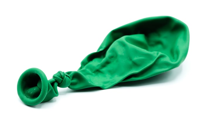 Deflated green balloon on a white background