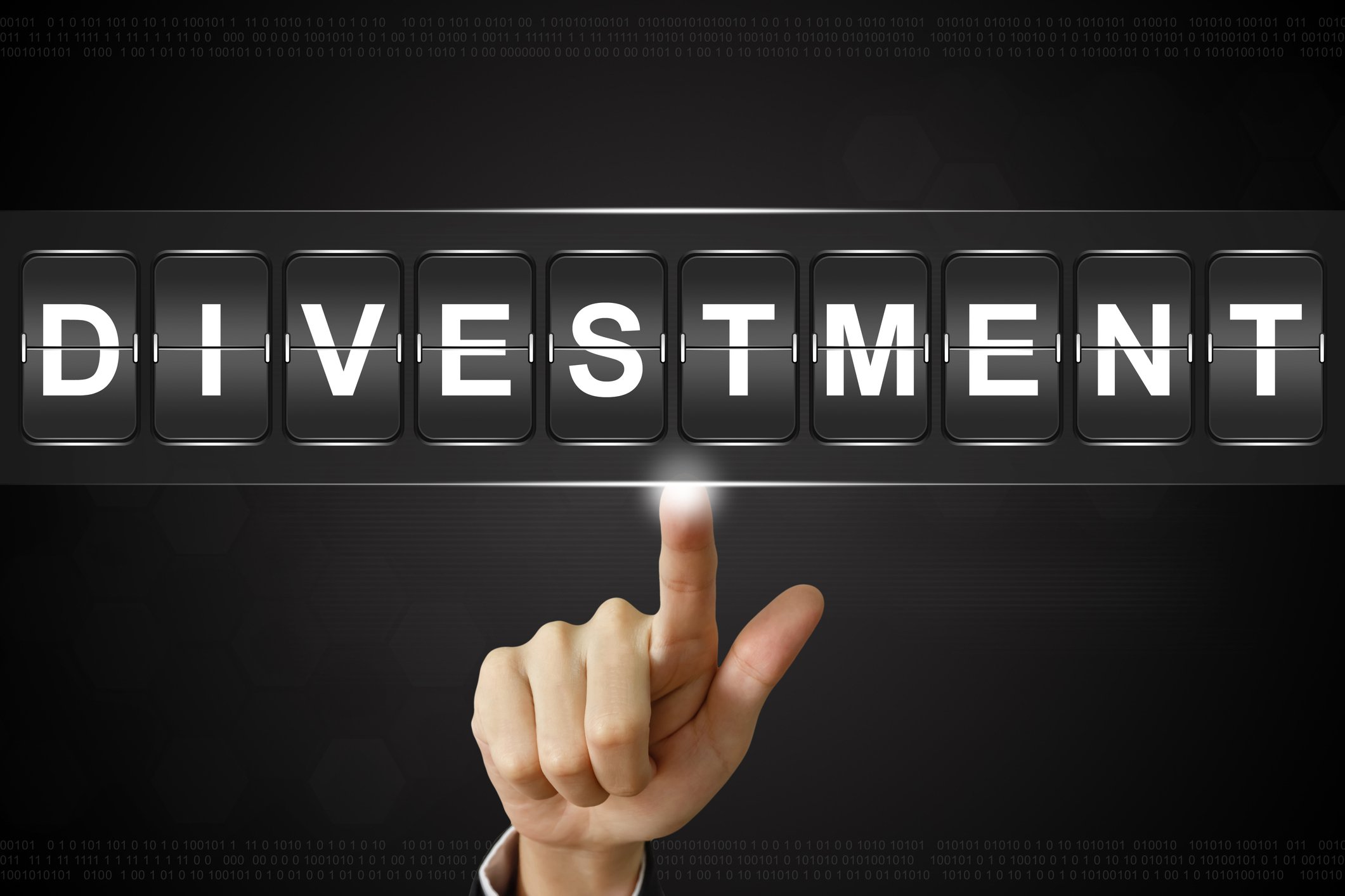 A hand emerging from a business suit sleeve clicking on a flipboard spelling out "Divestment." 