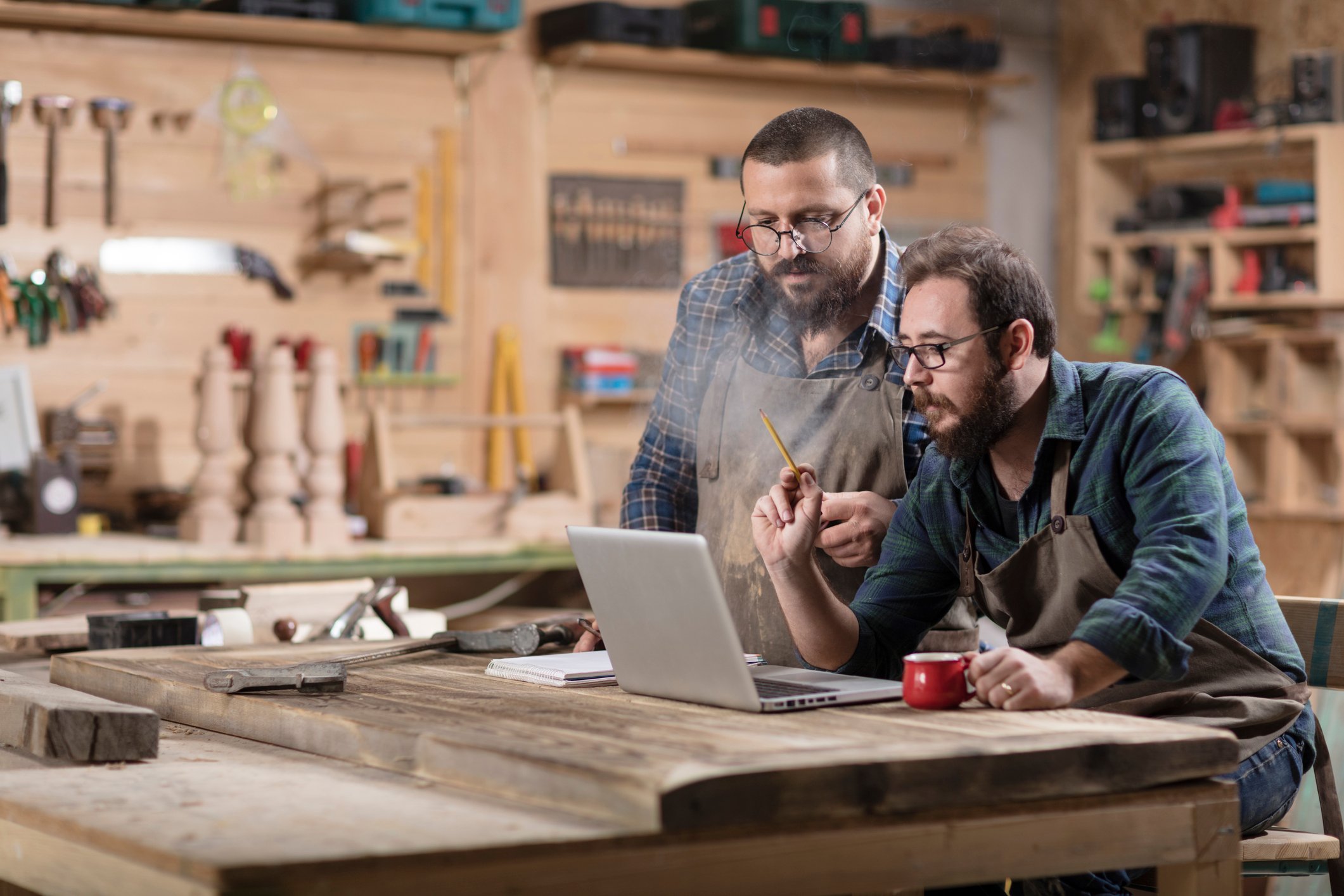 Two people in a wood shop looking at a laptop.