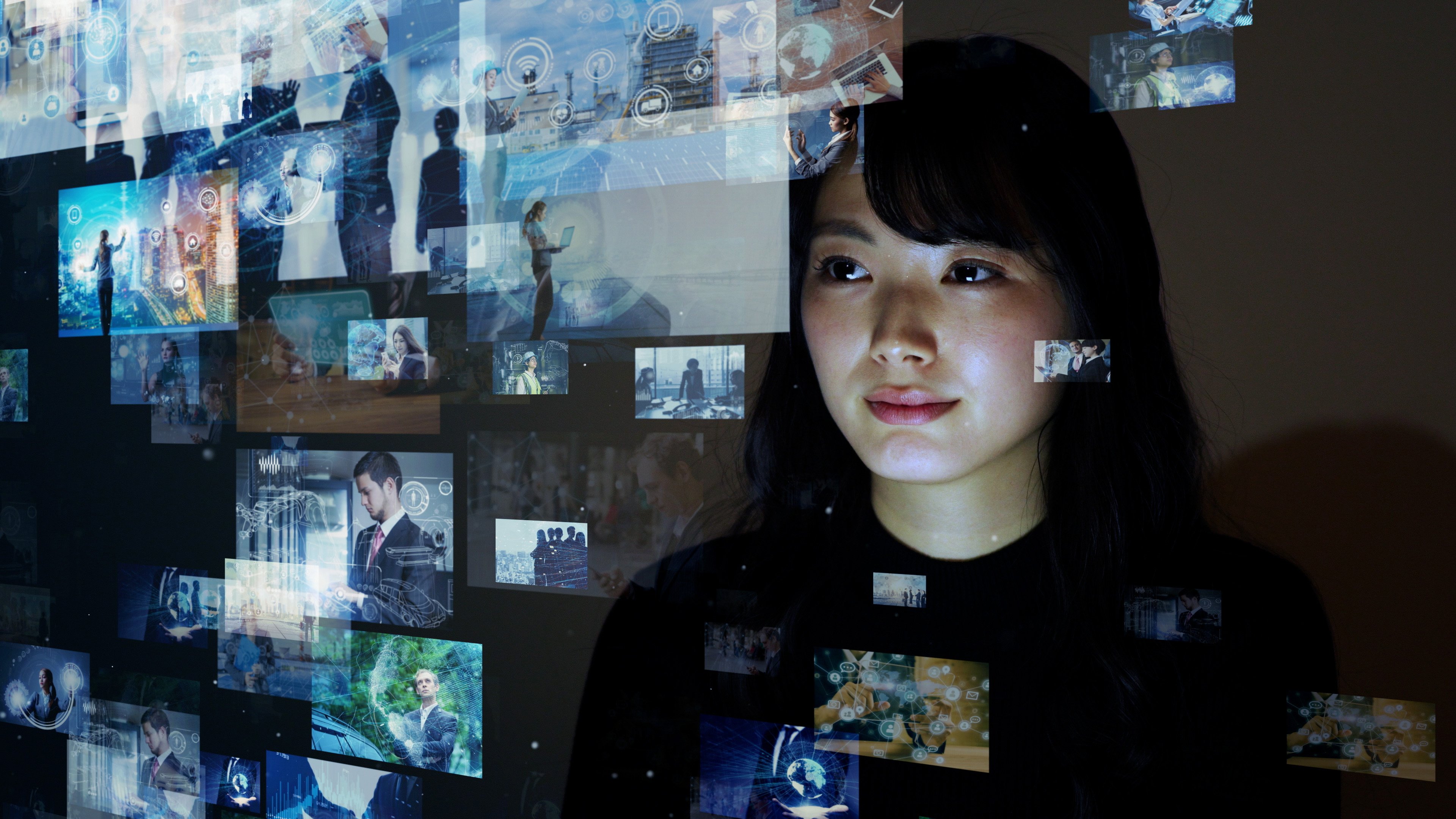 A woman looking at several TV screens on a glass wall.
