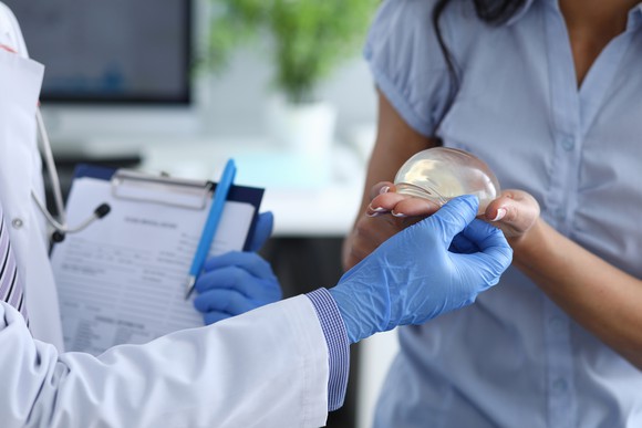 Patient and doctor inspecting silicone breast implant