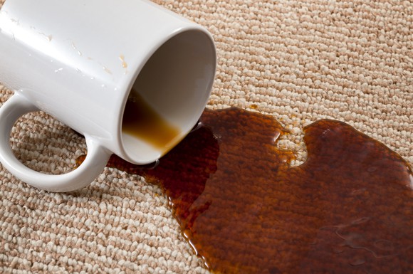 A spilled cup of coffee soaking into a carpet.