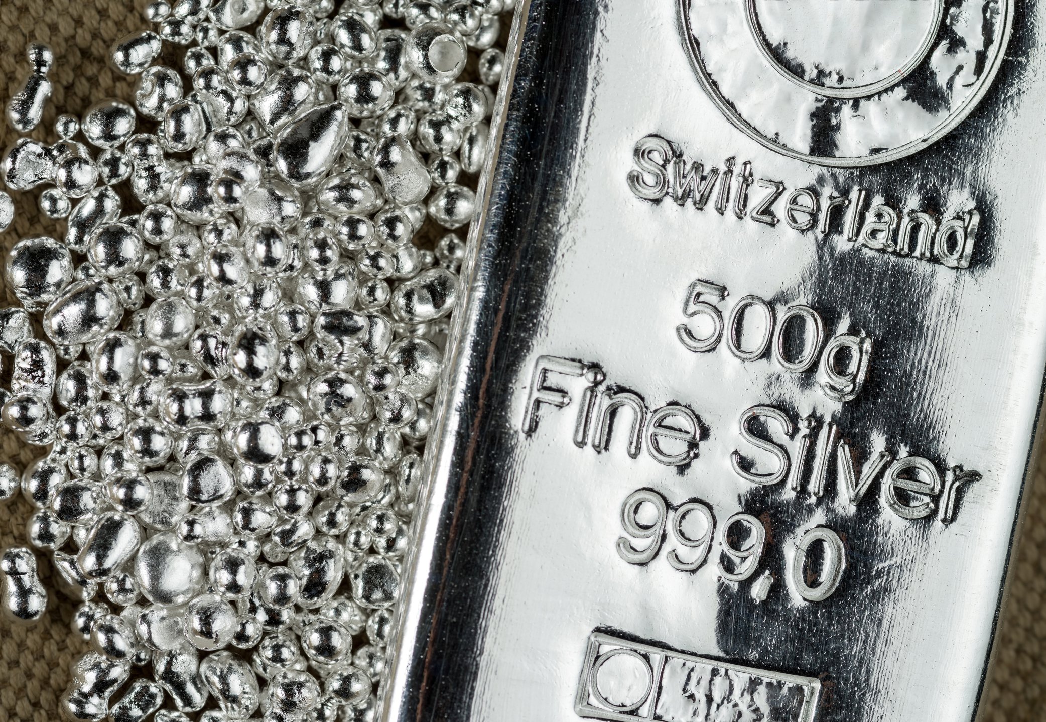 A silver bar beside a pile of silver grains.