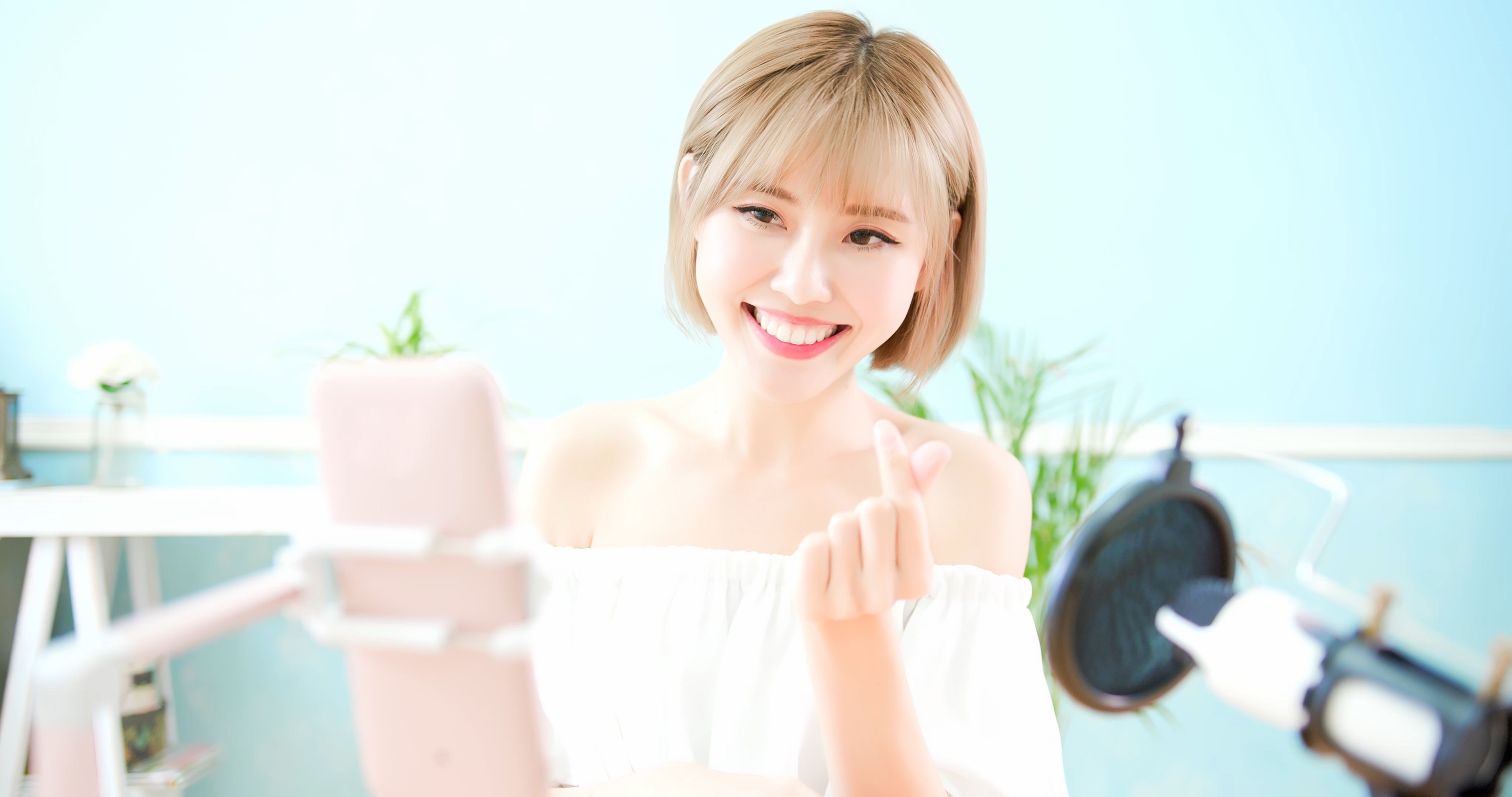 A young woman records a video on her smartphone.
