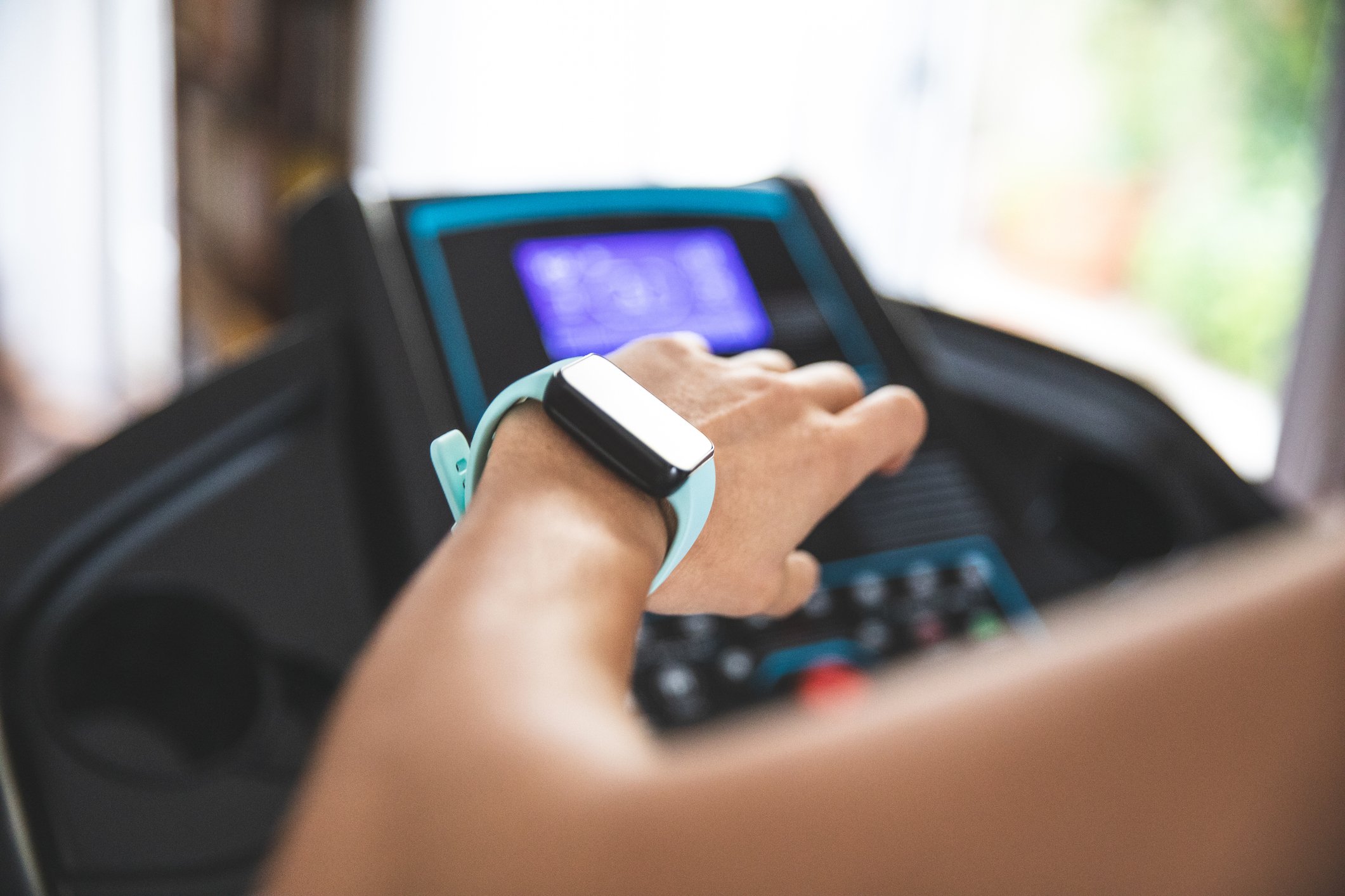 A woman looking at her watch on her wrist while using a treadmill.