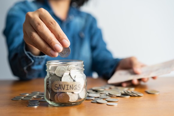 Woman putting coins in a jar labeled Savings