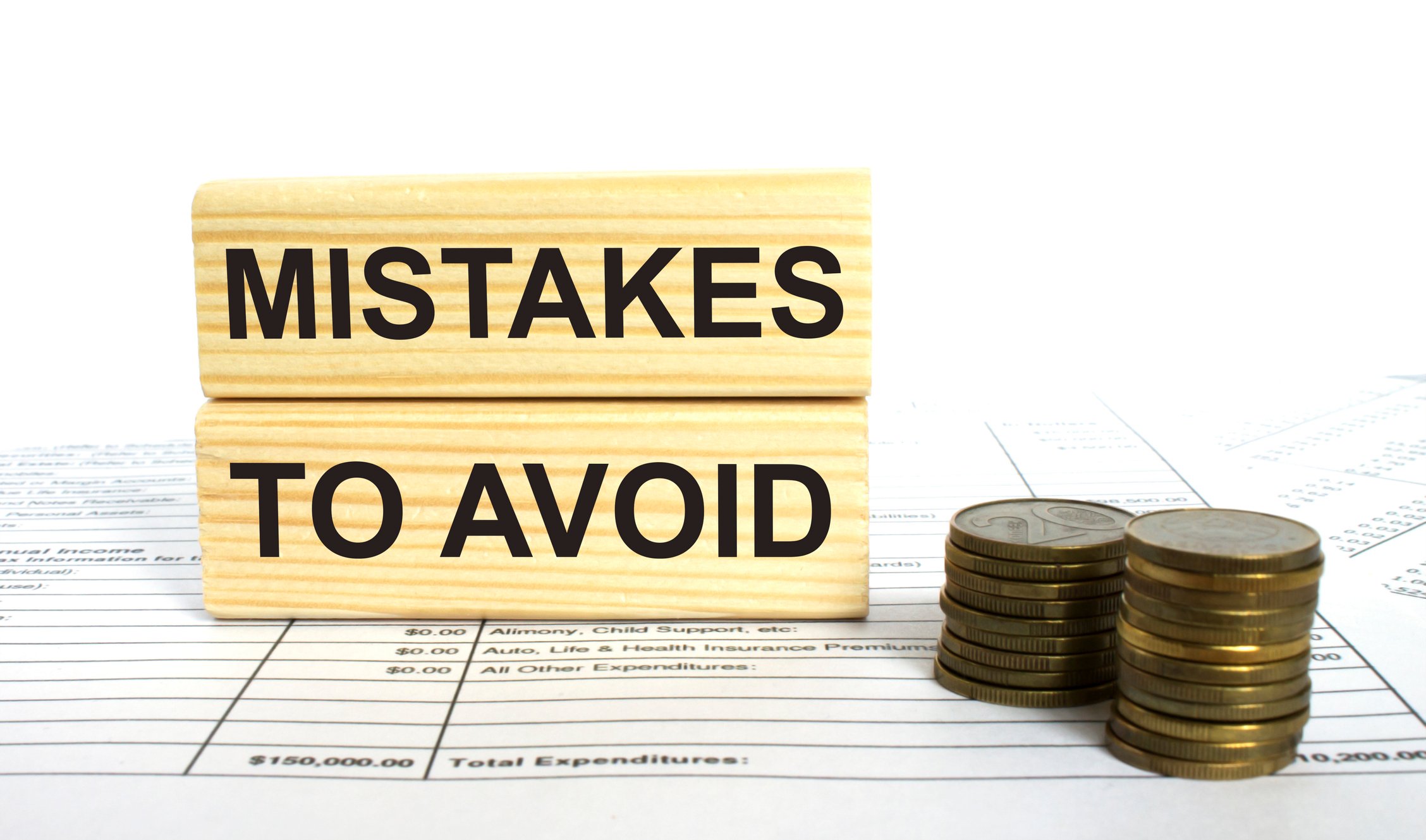 A sign that says mistakes to avoid next to two piles of coins.