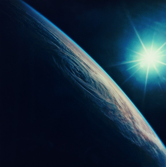 View of Earth from low orbit, with Sun in background.