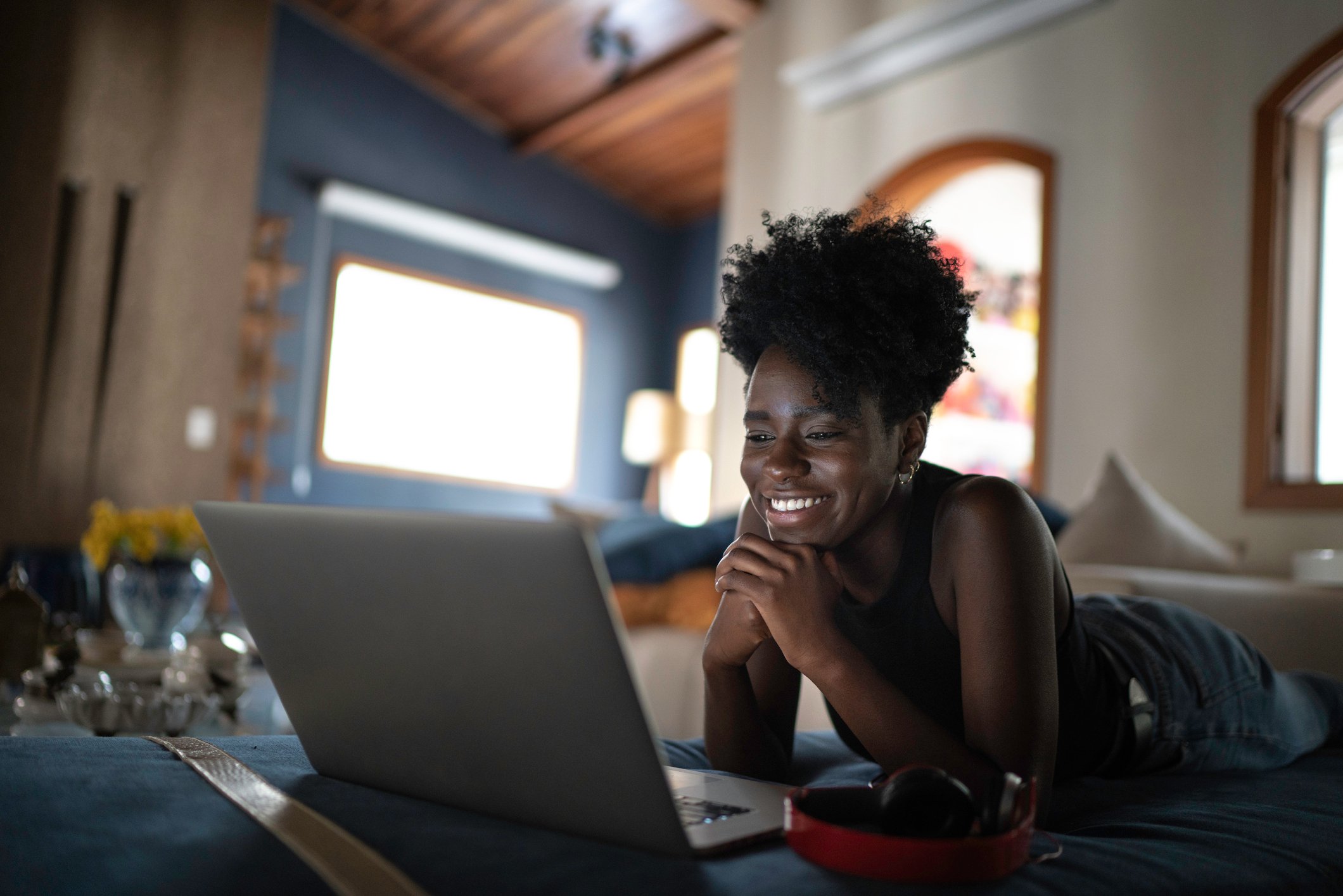 Woman lying on floor on her stomach, watching laptop