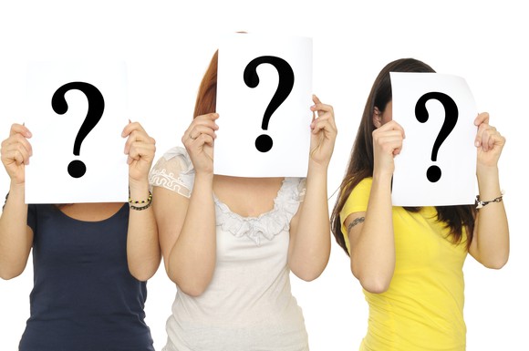 Three women holding up question marks in front of their faces