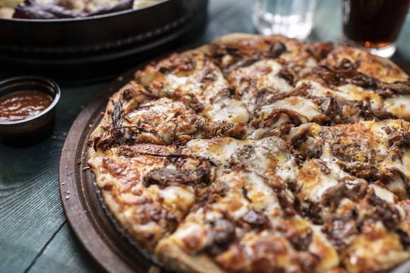 Meat pizza cut into eight slices sitting on a table