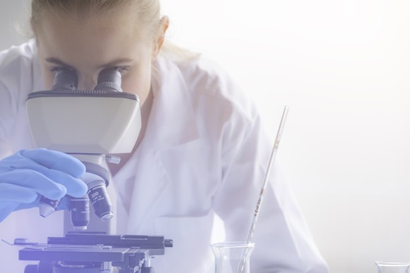 Scientist looking through microscope.