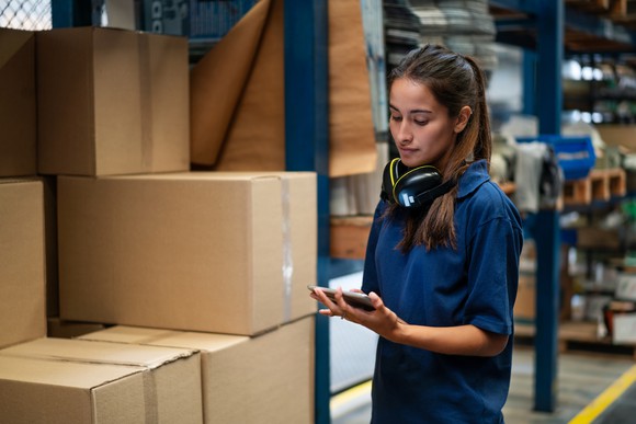 A warehouse worker monitors inventory on a tablet. 